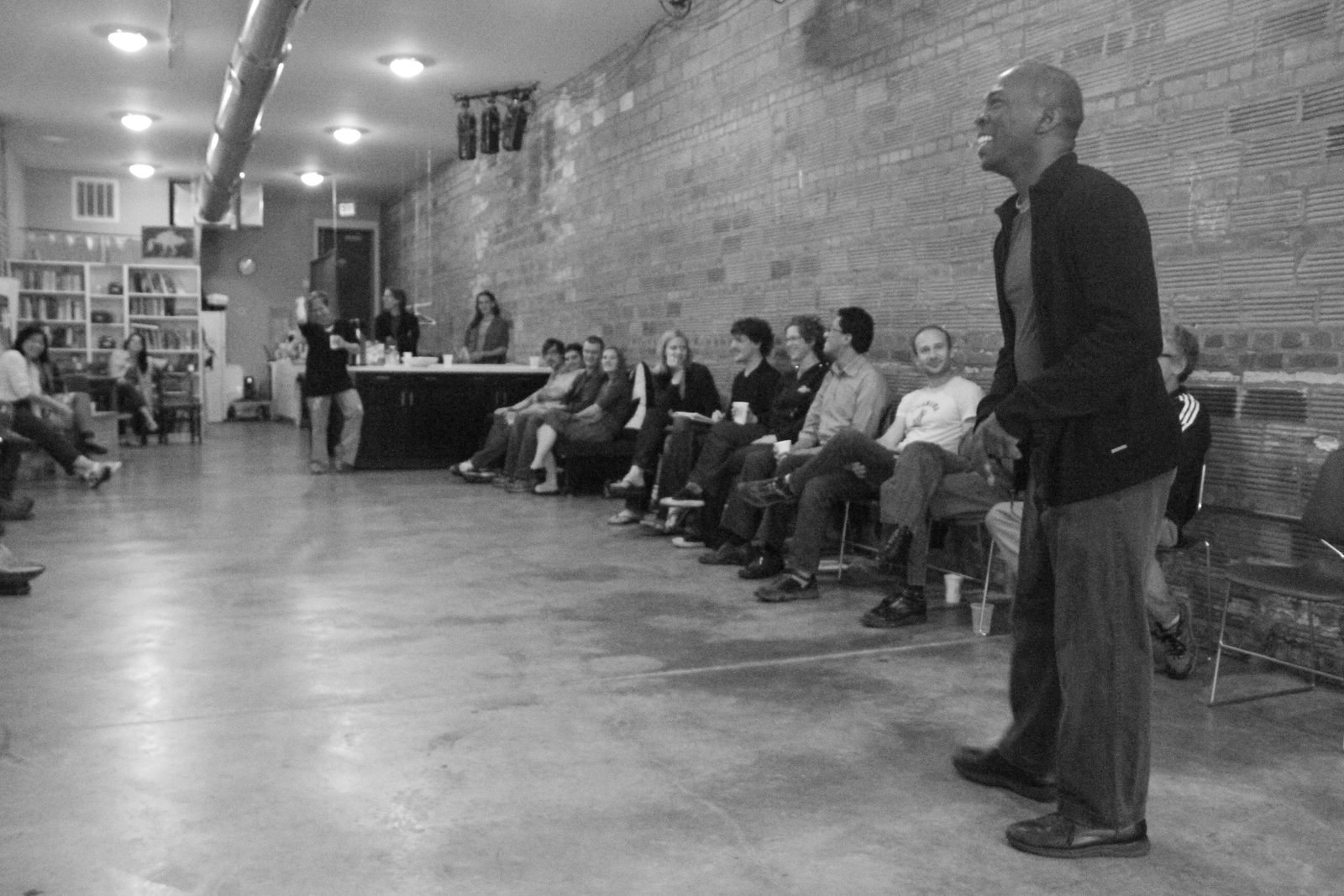Boris Willis standing and laughing as the seated audience looks on