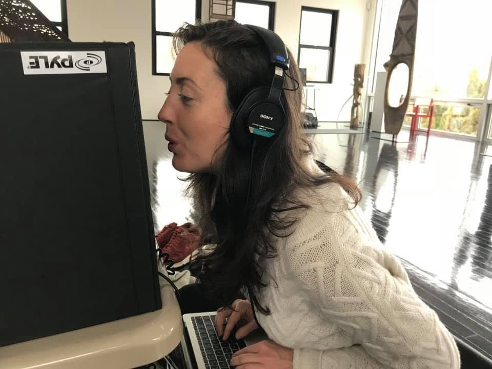 Erin Roy in headphones recording audio at a speaker in the Watermill Center